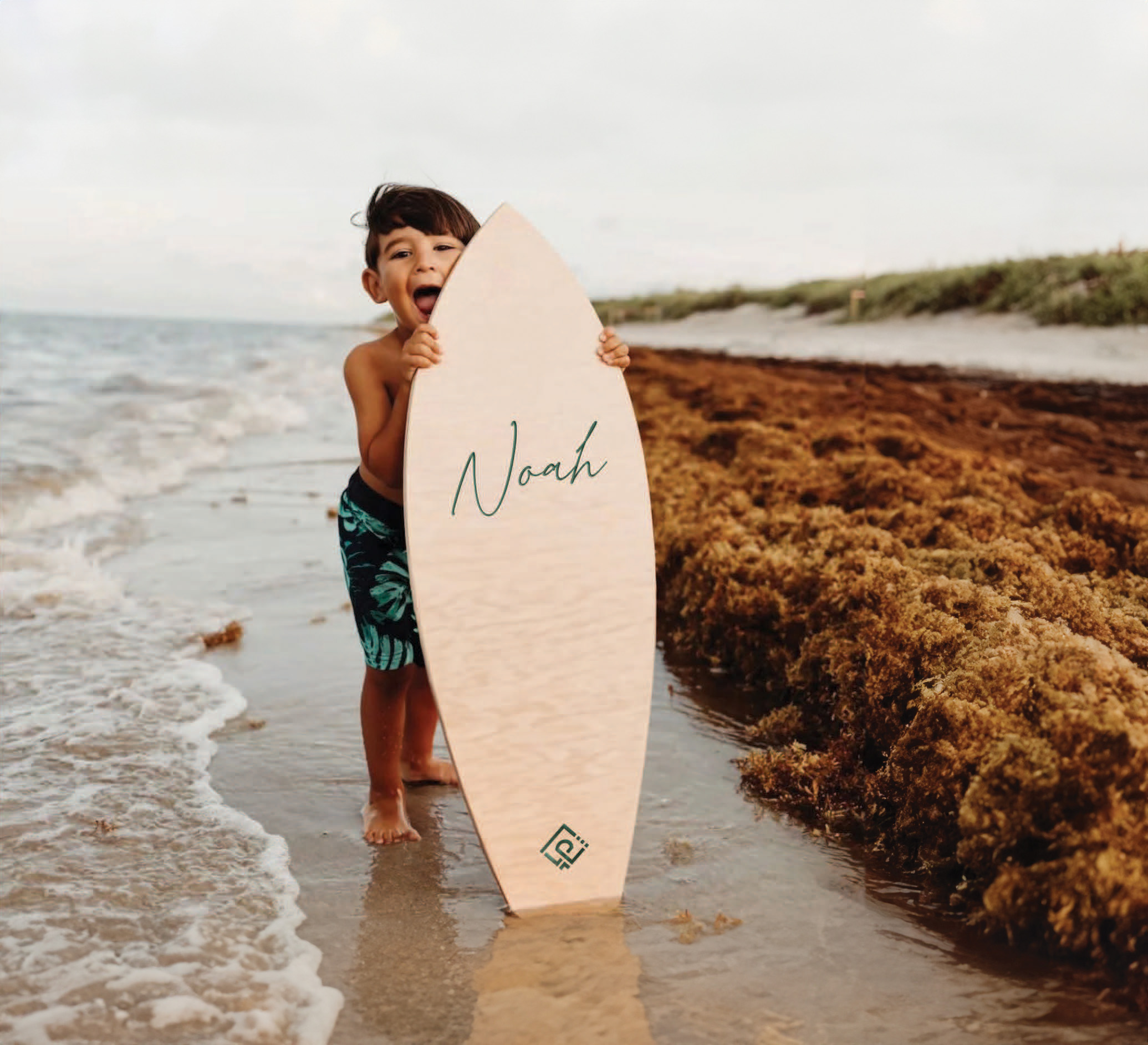 A boy on the beach with a surfboard.